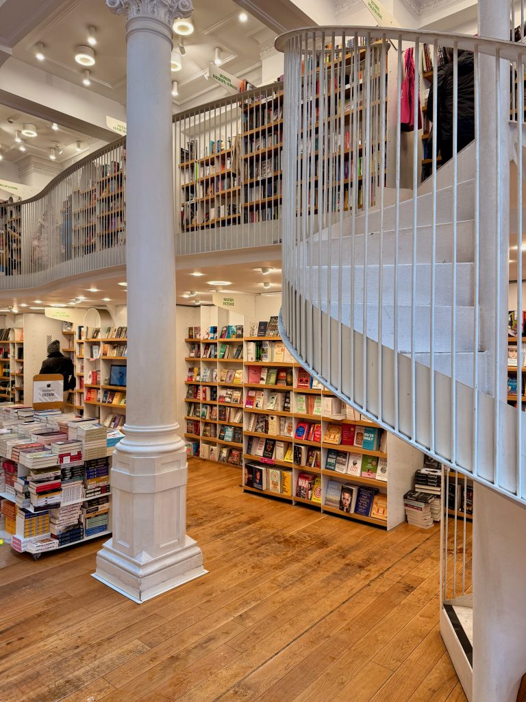 The elegant interior of Cărturești Carusel, Bucharest’s famous multi-level bookstore with white railings and warm wooden floors.