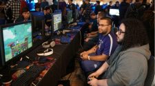 Players competing in an esports gaming tournament using consoles and monitors, surrounded by spectators in a competitive gaming environment.